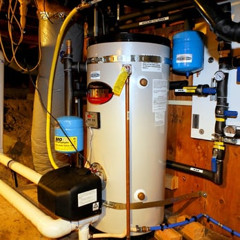 A neatly installed water heater with connected pipes and pressure tanks in a basement setting by Duncan Plumbing Ent., Inc. in Santa Cruz.